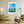 Descriptive Minimalist Malta Poster in Wooden Frame displayed in a living room with green chairs.